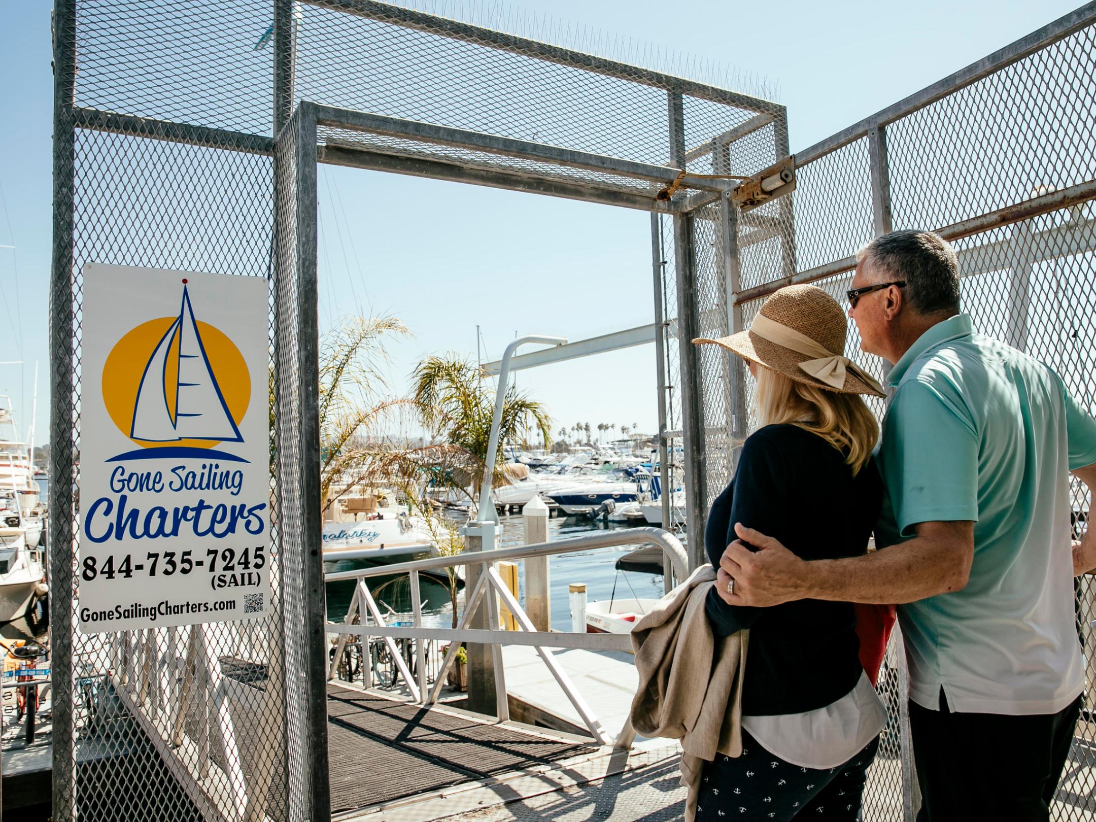 a man and a woman standing in front of a fence